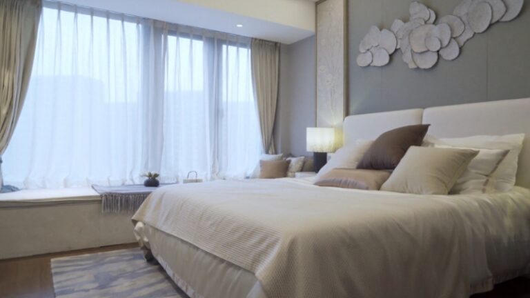 Mala spavaća soba sa velikim prozorima, mekanim jastucima i neutralnim tonovima