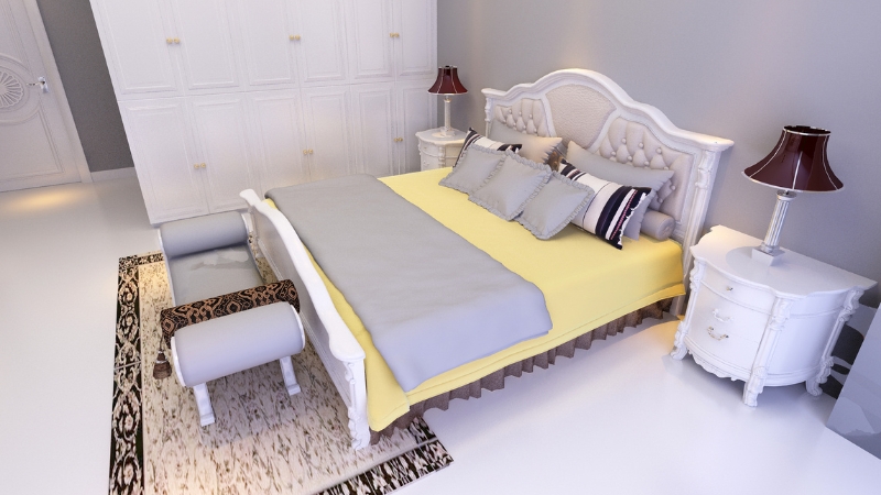 Mala spavaća soba sa velikim uzglavljem, žutom posteljinom i klasičnim belim nameštajem