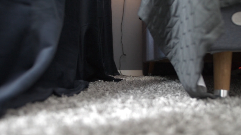 Prikaz poda u spavaćoj sobi sa mekanim sivim tepihom i krevetom na nogicama